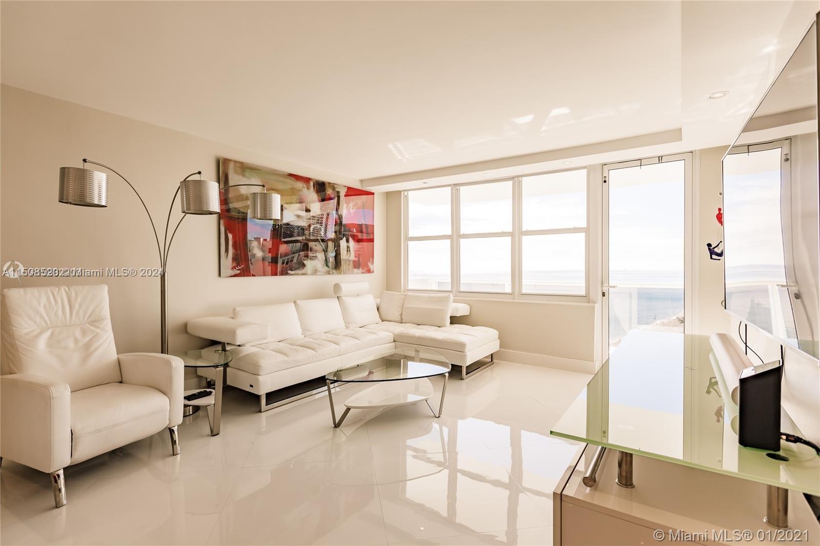 A modern living room features white leather furniture, a glass coffee table, and ocean views — 3725 S Ocean Dr # 1504, Hollywood FL 33019, HOLLYWOOD, FL
