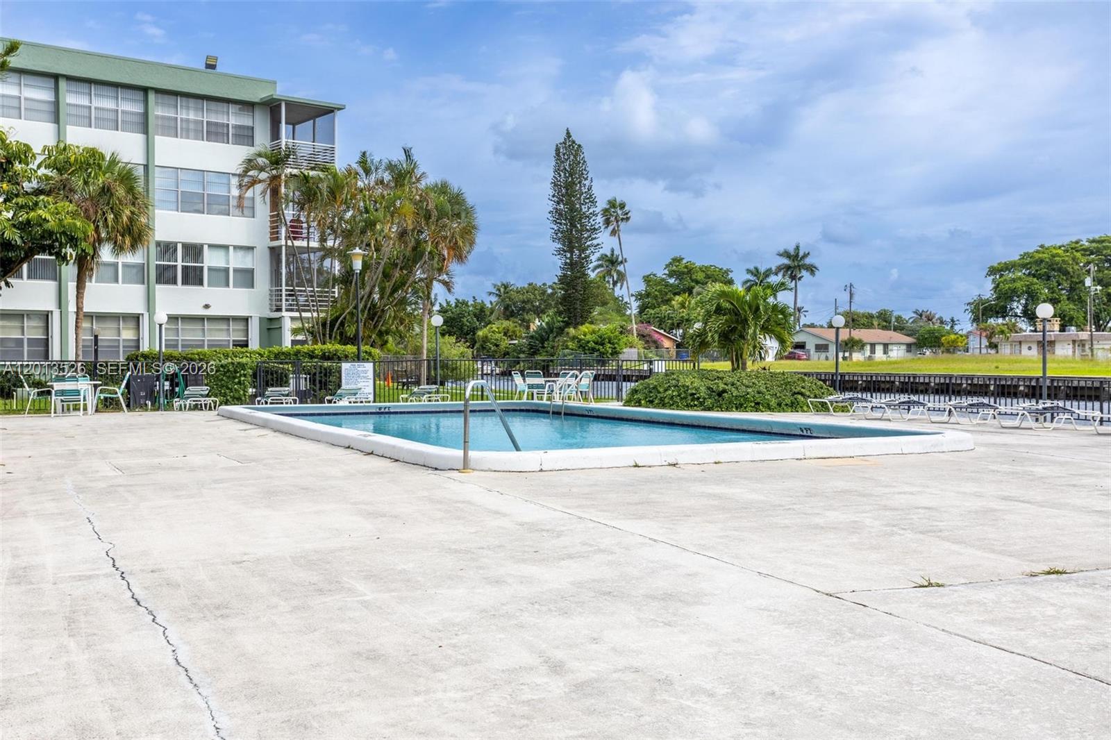An outdoor swimming pool is surrounded by a concrete deck and a multi-story apartment building — 2741 Taft St # 203, Hollywood FL 33020, HOLLYWOOD, FL