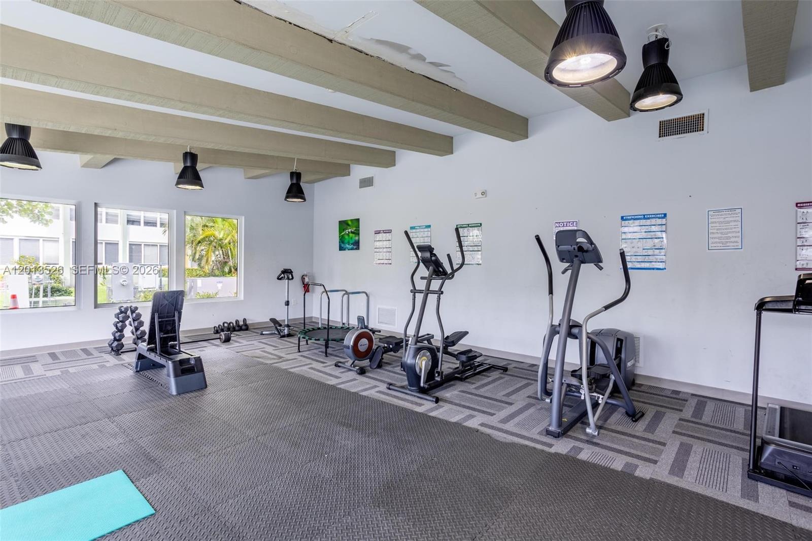 A gym room features exercise equipment, rubber flooring, exposed ceiling beams, and large windows — 2741 Taft St # 203, Hollywood FL 33020, HOLLYWOOD, FL