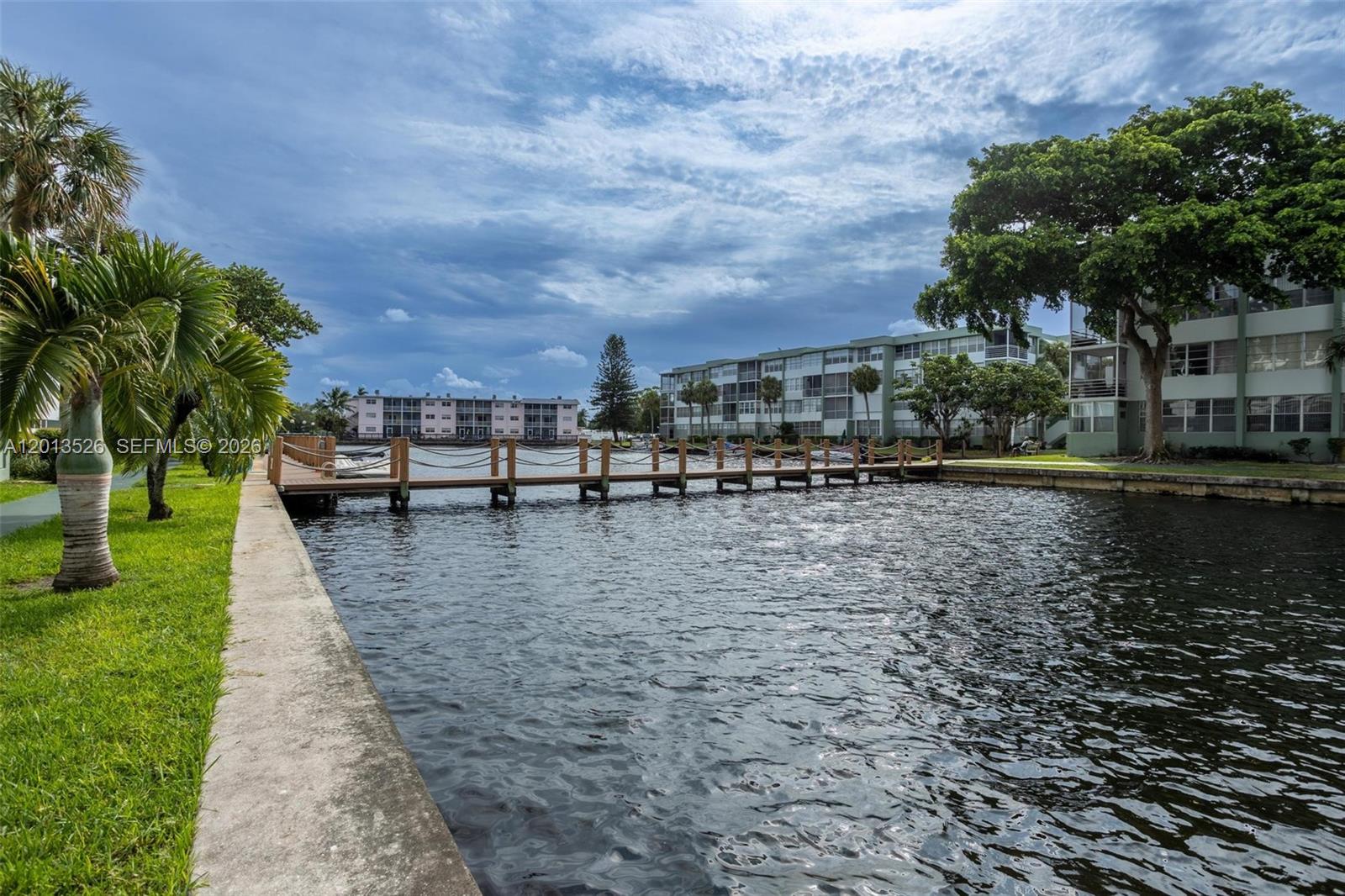 A wooden dock extends into a canal between two multi-story apartment buildings — 2741 Taft St # 203, Hollywood FL 33020, HOLLYWOOD, FL