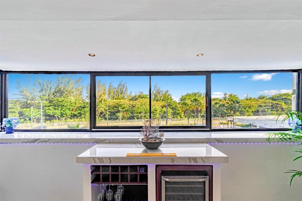 A bar area with a marble countertop sits in front of a large window overlooking trees — 7185 COND. MAR DE ISLA VERDE UNIT 3A, CAROLINA, PR