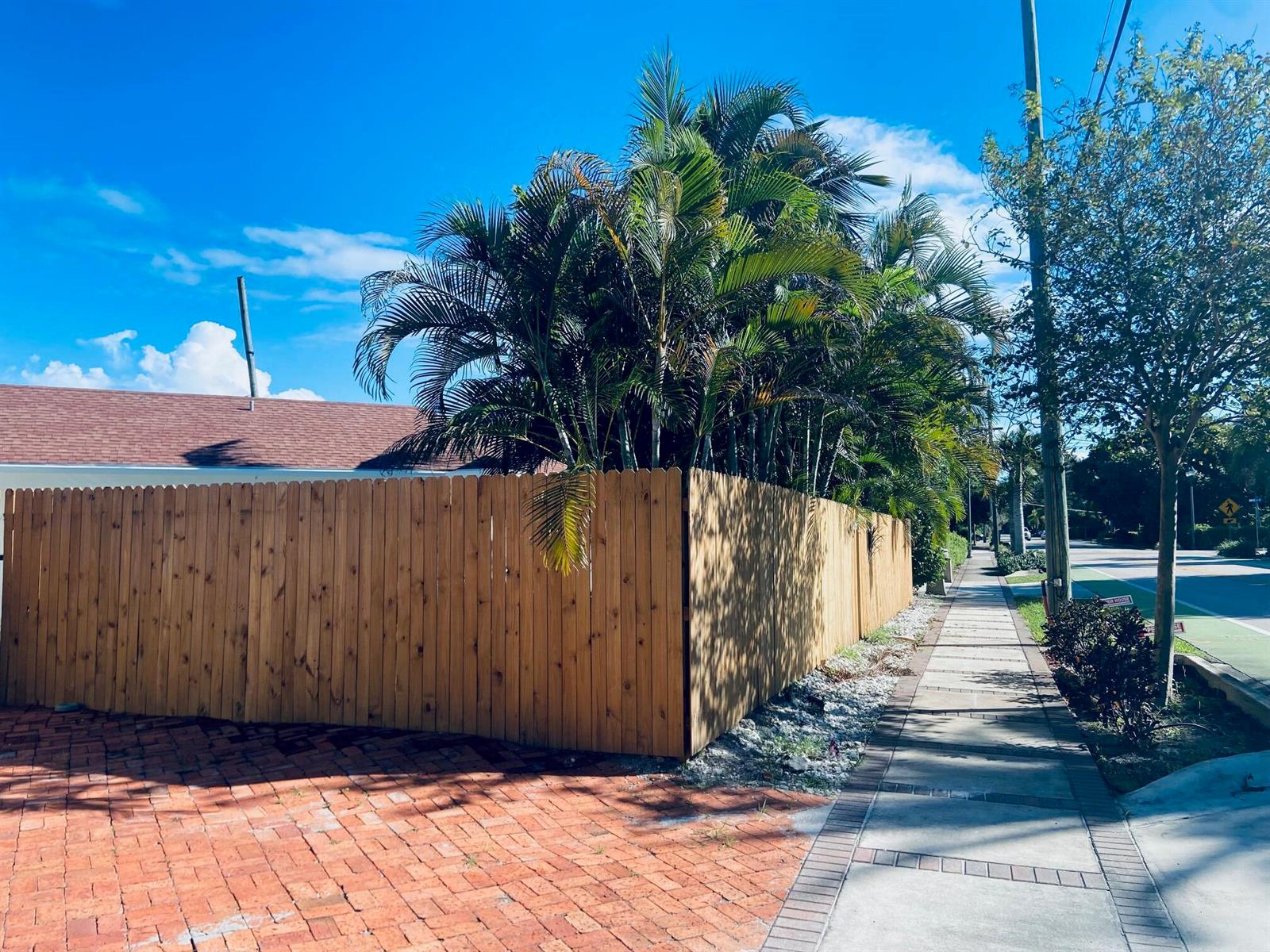 A wooden fence encloses a property with palm trees next to a sidewalk and street — 615 NE 2nd Avenue, Delray Beach FL 33444, DELRAY BEACH, FL