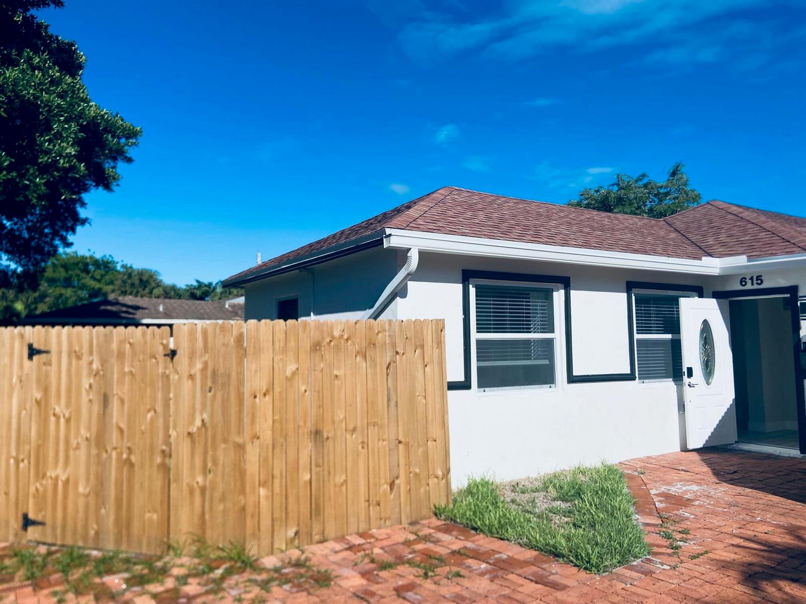 A white house with a brown roof, black window trim, and a wooden privacy fence — 615 NE 2nd Avenue, Delray Beach FL 33444, DELRAY BEACH, FL