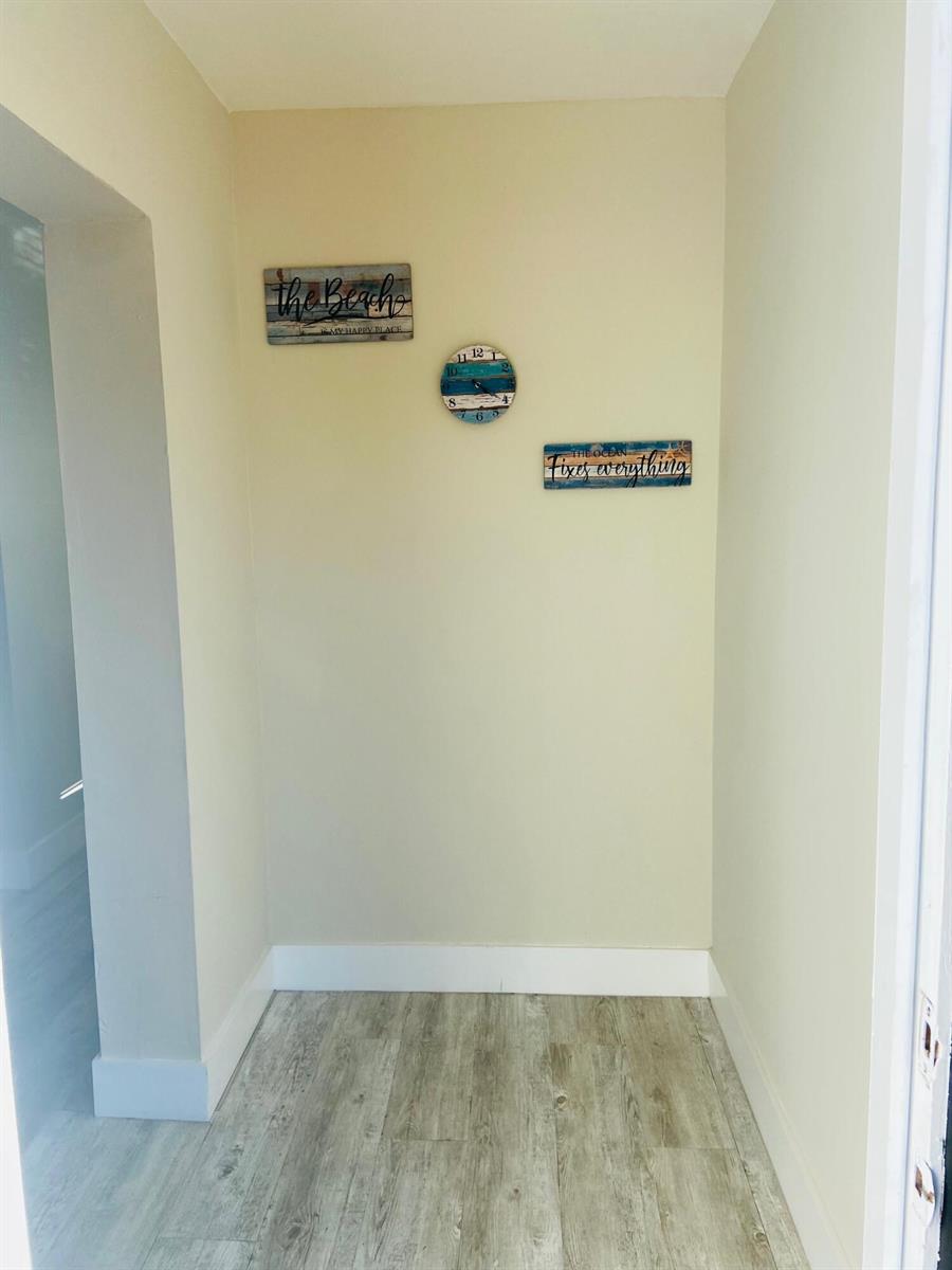 A small entryway features light-colored walls, wood-look flooring, and beach-themed wall decor — 615 NE 2nd Avenue, Delray Beach FL 33444, DELRAY BEACH, FL