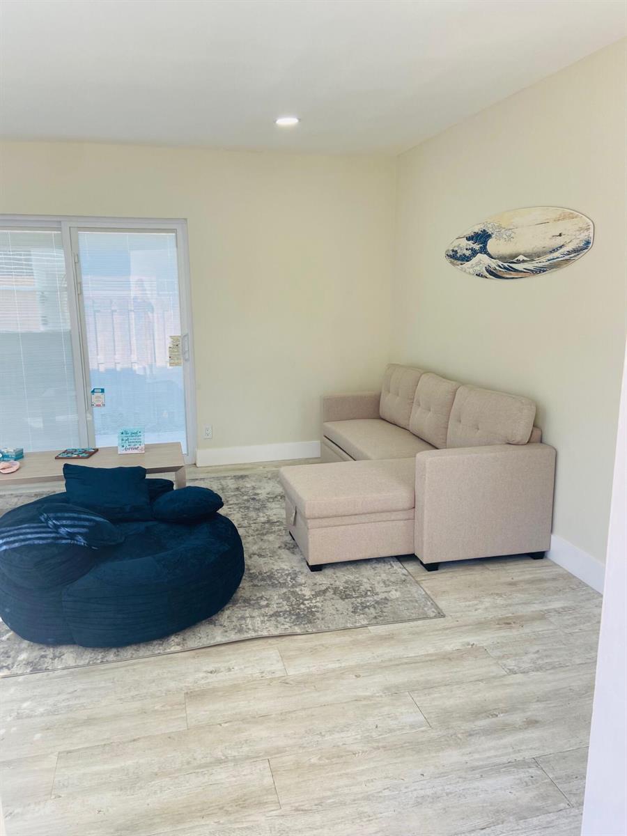 A living room features a beige sectional sofa, a large navy blue beanbag, and wood-look flooring — 615 NE 2nd Avenue, Delray Beach FL 33444, DELRAY BEACH, FL