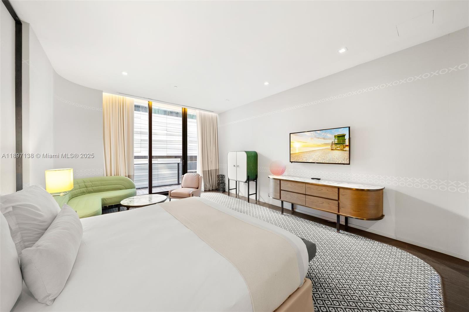 A modern bedroom features a bed, a green sofa, a television, and a patterned rug — 801 S Miami Ave # 402, Miami FL 33130, MIAMI, FL