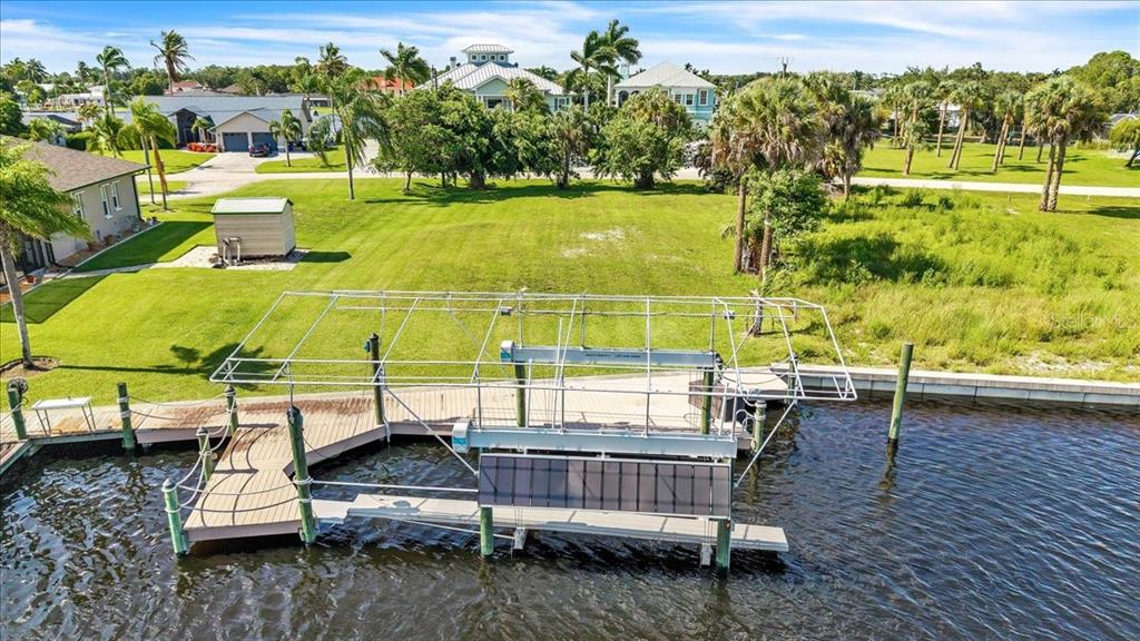 An aerial view shows a boat lift and dock extending into a canal beside a lawn — 13425 MARQUETTE BOULEVARD, FORT MYERS, FL