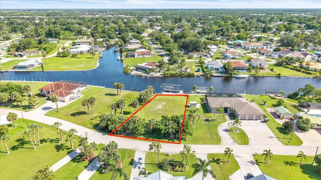 An aerial view shows a vacant waterfront lot outlined in red between two residential houses — 13425 MARQUETTE BOULEVARD, FORT MYERS, FL