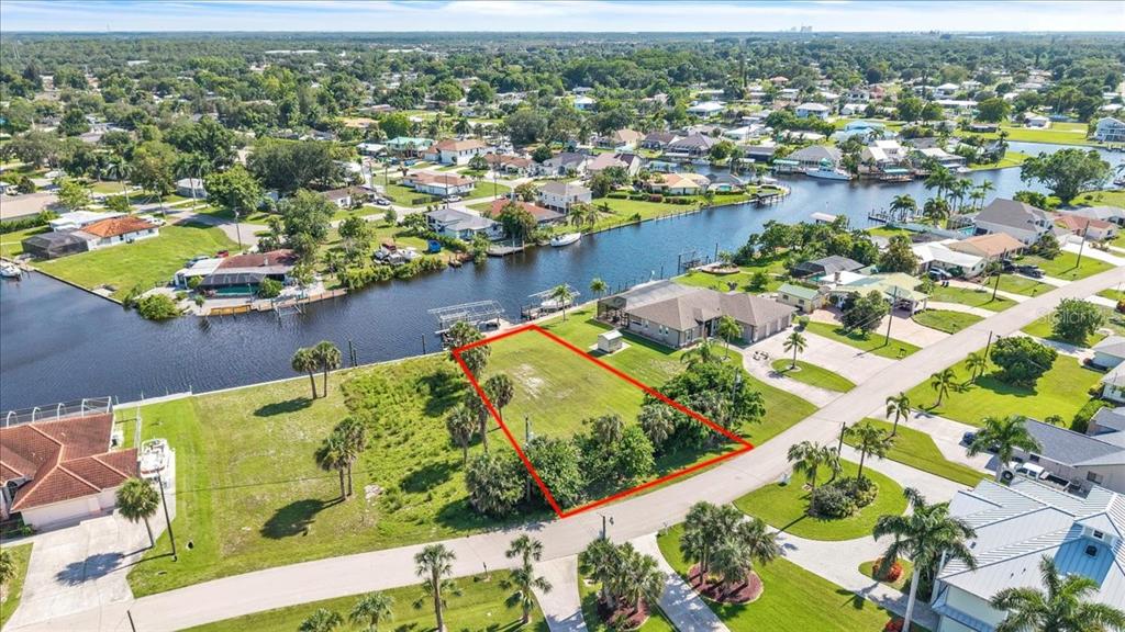 An aerial view shows a vacant waterfront lot outlined in red in a residential neighborhood — 13425 MARQUETTE BOULEVARD, FORT MYERS, FL