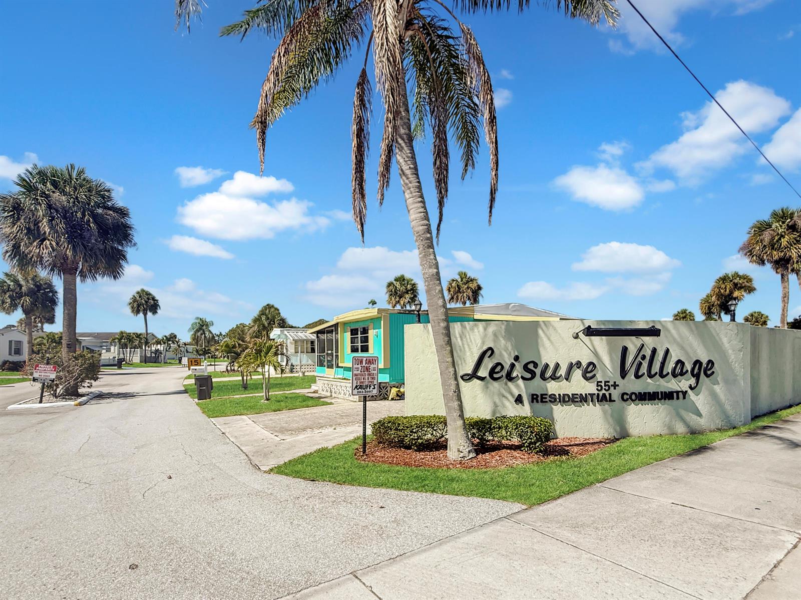 The entrance sign for Leisure Village 55+ residential community stands beside a palm tree — 143 SE Easy Street, Stuart FL 34994, STUART, FL