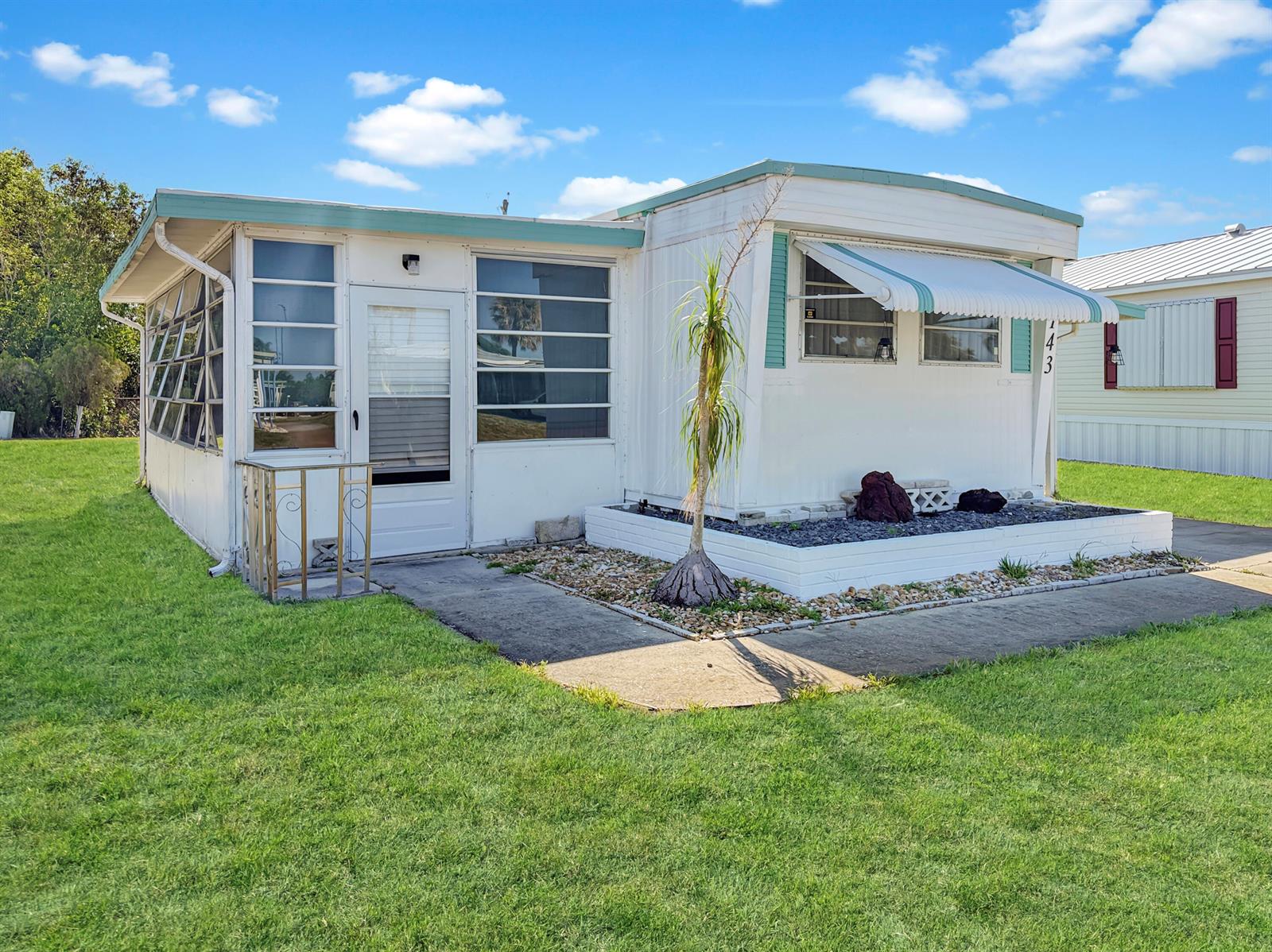 A white mobile home with a screened-in porch and a small front garden area — 143 SE Easy Street, Stuart FL 34994, STUART, FL