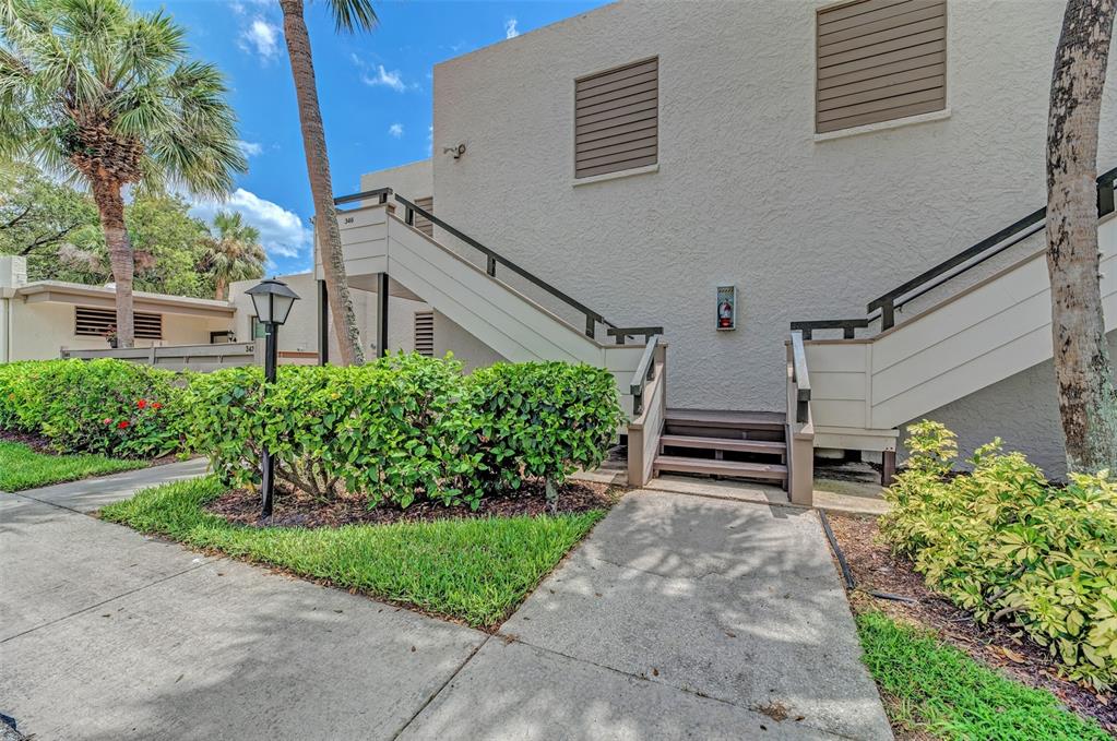 An exterior view of a two-story building with an outdoor staircase and surrounding landscaping — 346 SPRINGDALE DRIVE W UNIT 346, BRADENTON, FL