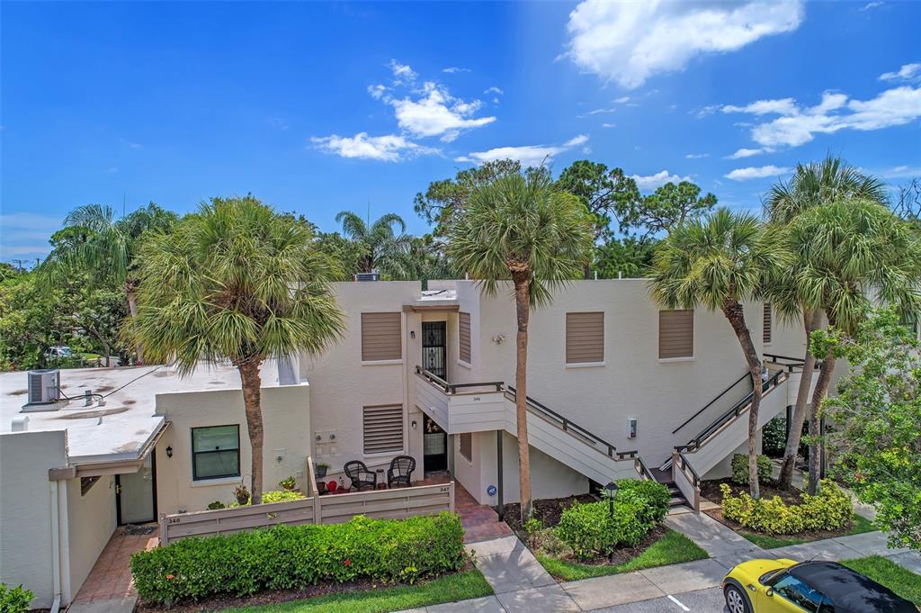 An exterior view of a two-story apartment building with palm trees and a staircase — 346 SPRINGDALE DRIVE W UNIT 346, BRADENTON, FL