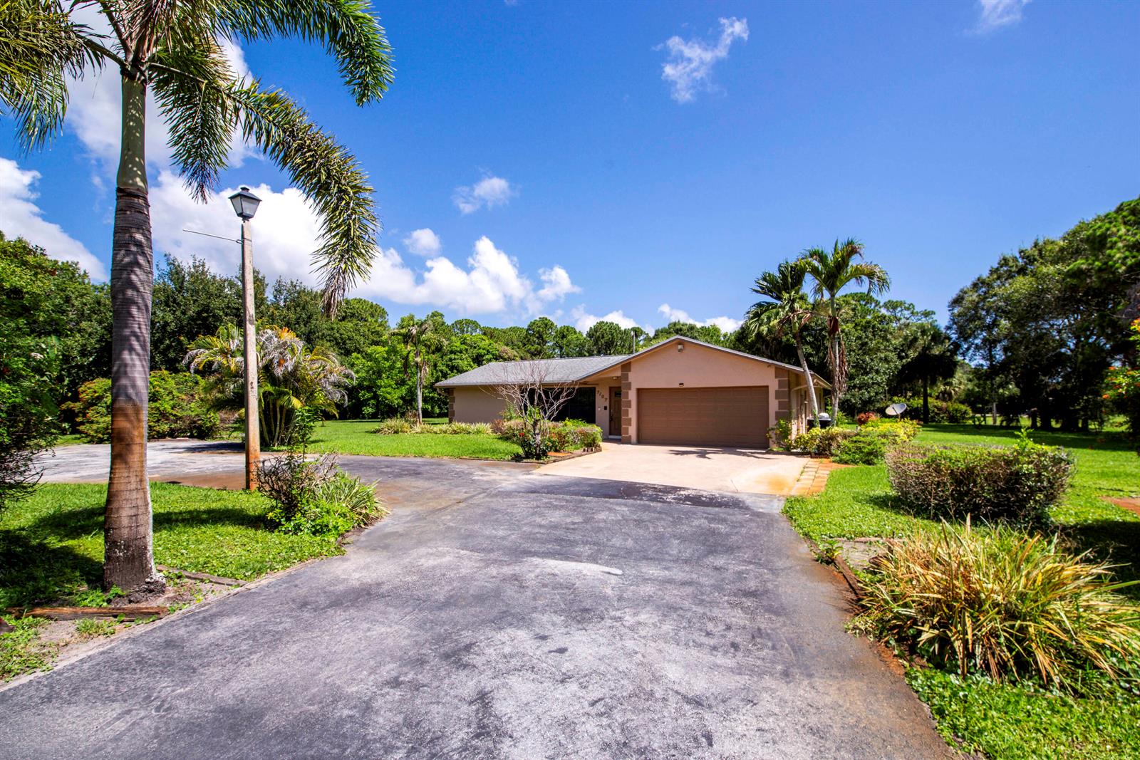 A single-story house with a two-car garage and a paved driveway surrounded by trees — 7107 181st Street N, Jupiter FL 33458, JUPITER, FL