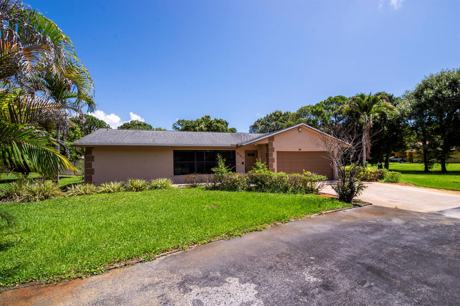 A single-story house with a tan exterior, a gray roof, and a paved driveway — 7107 181st Street N, Jupiter FL 33458, JUPITER, FL