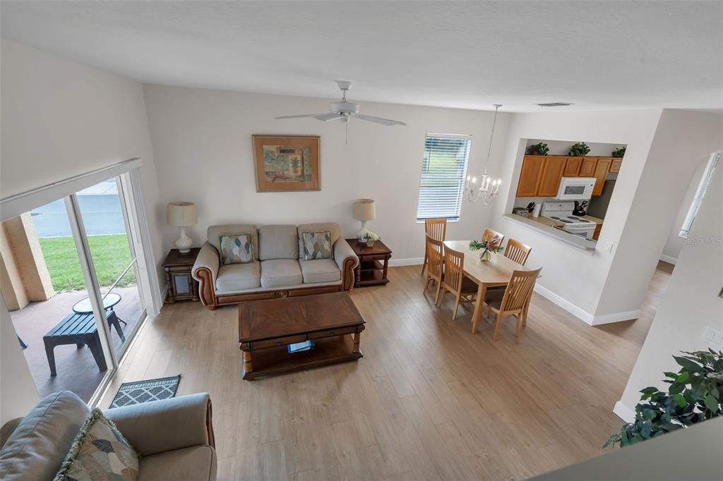 An open-concept living and dining area features light wood flooring and a kitchen pass-through window — 743 CALABRIA AVENUE, DAVENPORT, FL