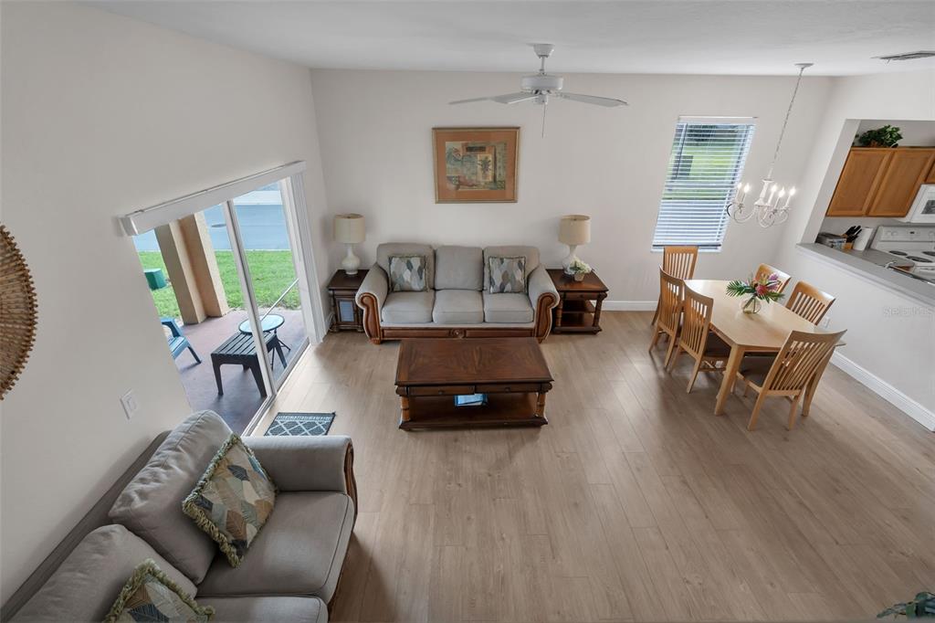An open-concept living and dining area features light wood flooring, neutral walls, and sliding doors — 743 CALABRIA AVENUE, DAVENPORT, FL