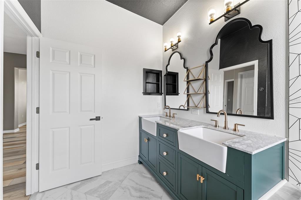 A modern shower features wood-look tile, black geometric accent tiles, and a gold rainfall showerhead — 1291 BLACKRUSH DRIVE, TARPON SPRINGS, FL
