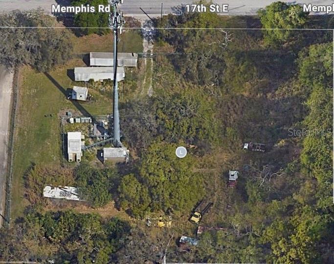 This aerial view shows a plot of land featuring a cell tower and several structures — 2103 & 2125 17TH STREET E, PALMETTO, FL