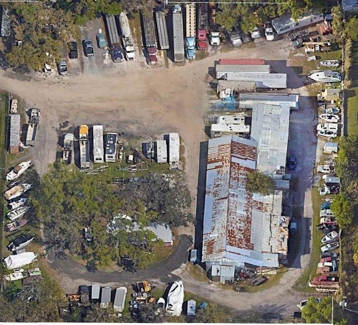 This aerial view shows a large industrial lot with a warehouse, trailers, and parked vehicles — 2103 & 2125 17TH STREET E, PALMETTO, FL
