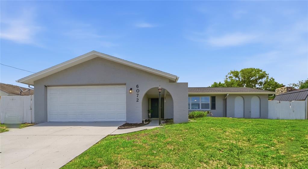 A single-story gray house with a two-car garage and an arched entryway — 6072 AIRMONT DRIVE, SPRING HILL, FL