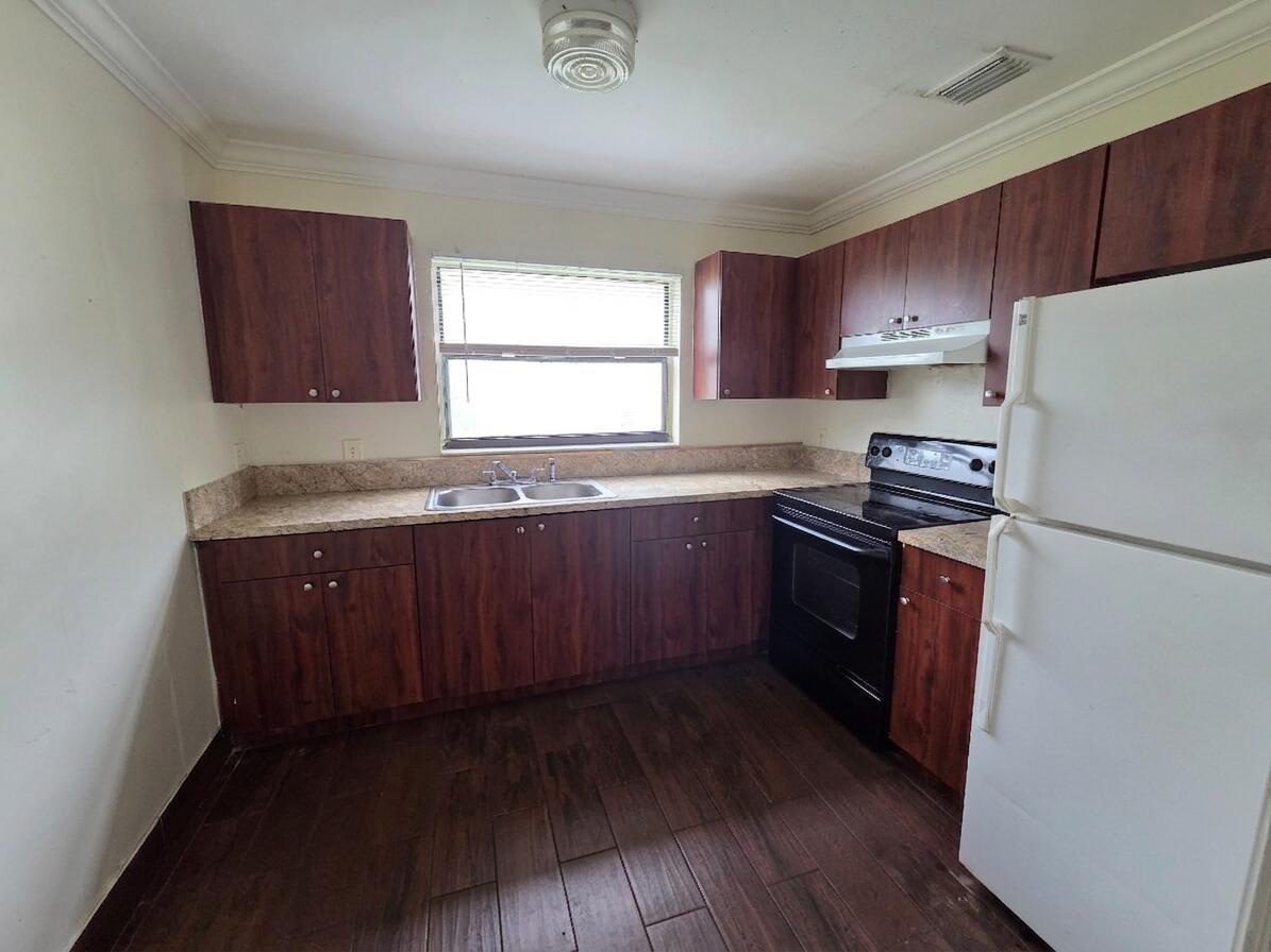 A kitchen features dark wood cabinets, laminate countertops, black appliances, and wood-look tile flooring — 3762 Mil Race Court, FL 33463, FL