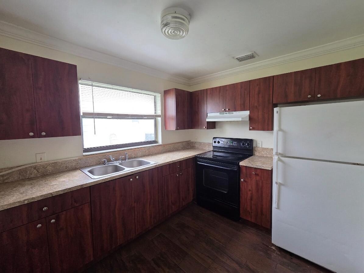 A kitchen with wood-look cabinets, laminate countertops, a double sink, and black and white appliances — 3762 Mil Race Court, FL 33463, FL