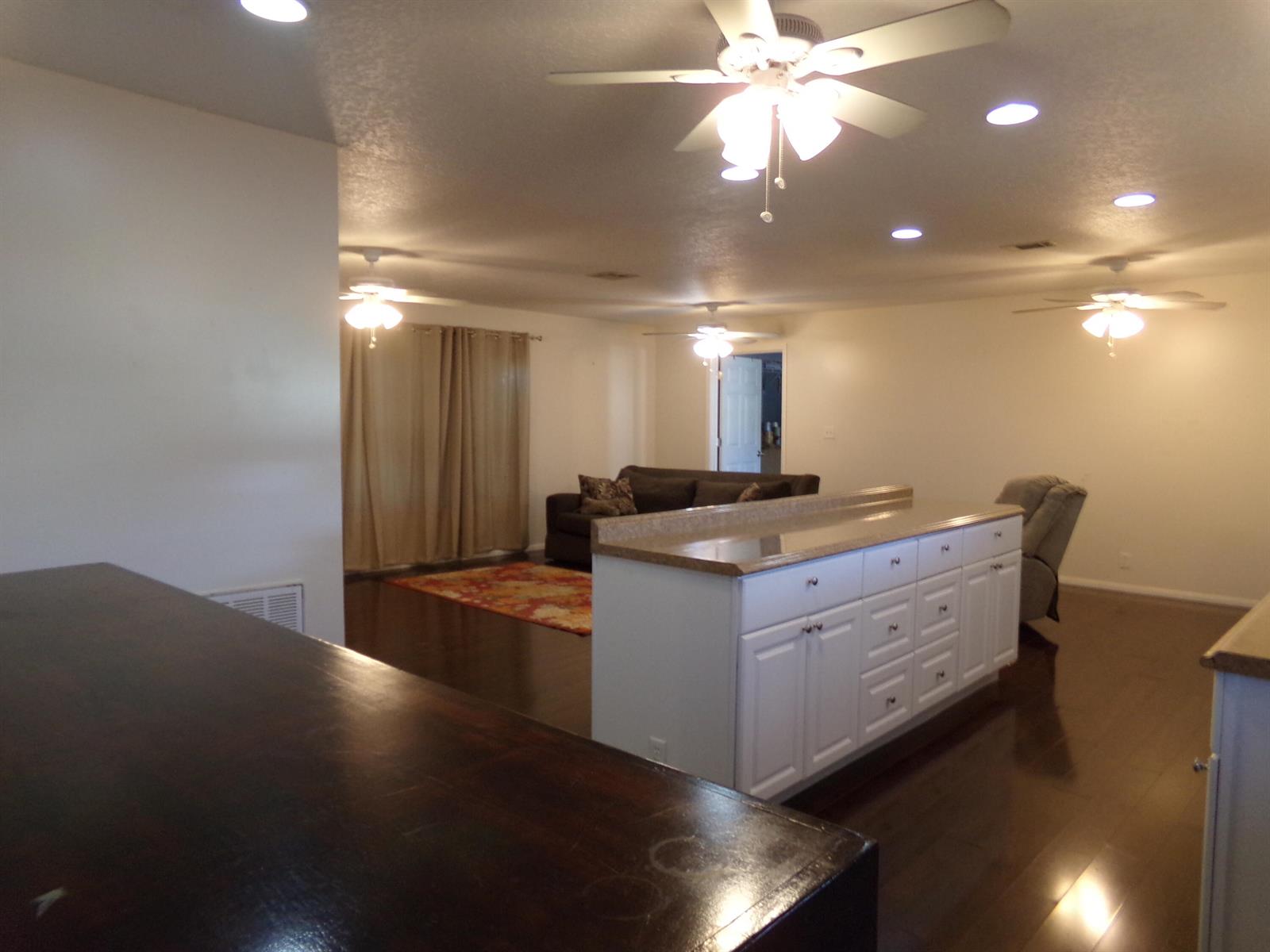 A kitchen island with white cabinets and a countertop faces a living area with hardwood floors — 52004 Florinada Bay, Boynton Beach FL 33436, BOYNTON BEACH, FL