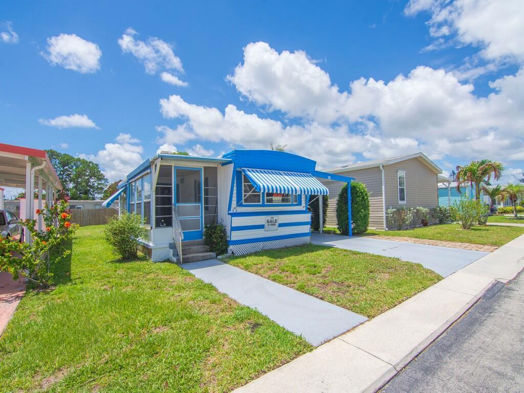 A blue and white mobile home with a striped awning sits on a grassy lot — 4800 Federal Highway # 43, Stuart FL 34997, STUART, FL