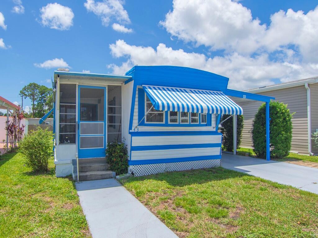 A blue and white mobile home with a screened porch, striped awning, and attached carport — 4800 Federal Highway # 43, Stuart FL 34997, STUART, FL
