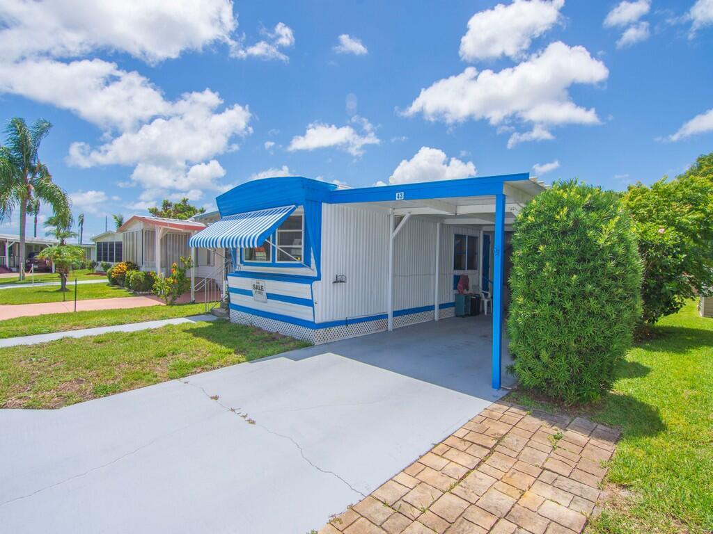 A single-story mobile home with a blue-trimmed exterior, carport, and a paved driveway — 4800 Federal Highway # 43, Stuart FL 34997, STUART, FL