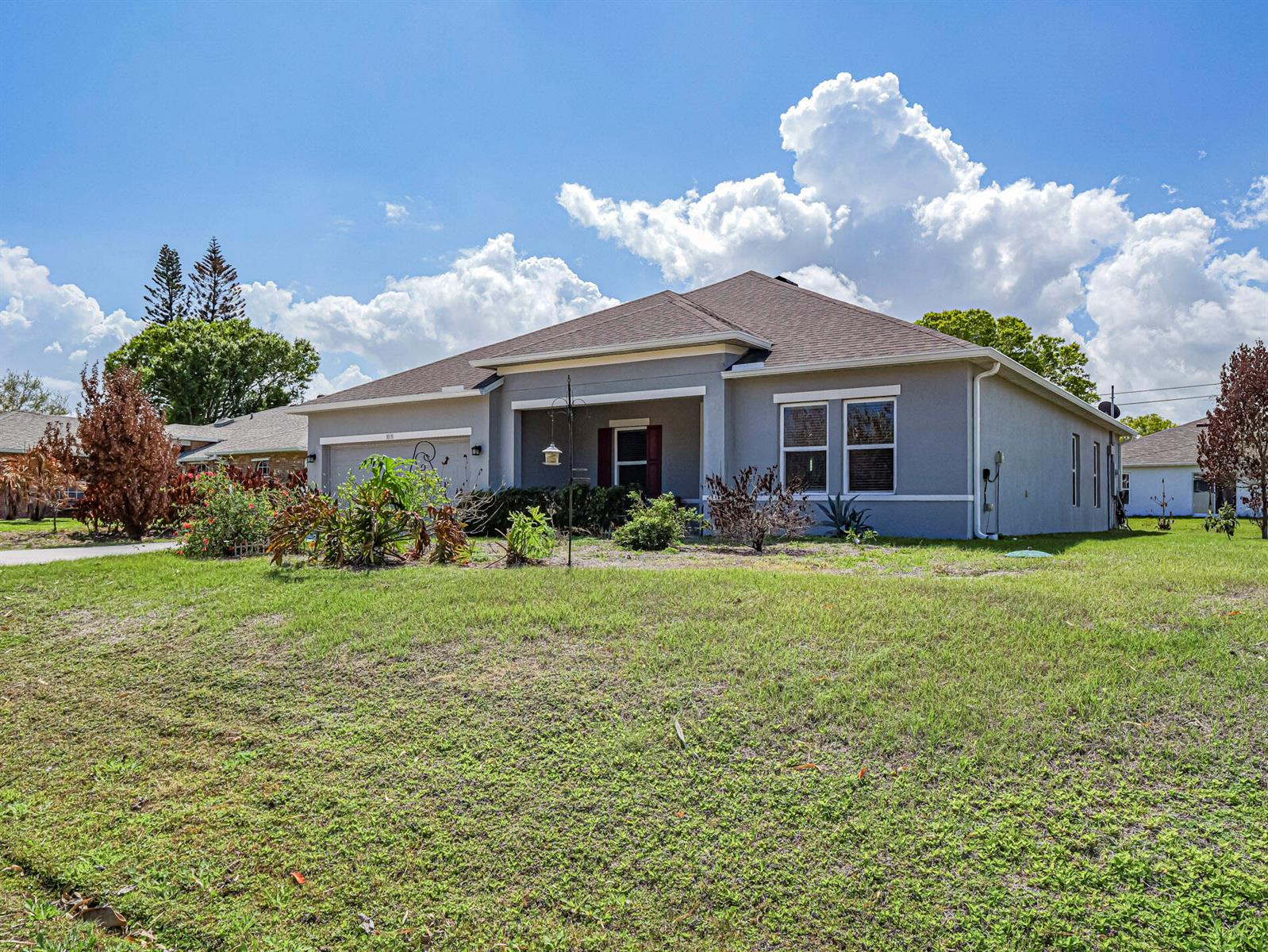 A single-story gray house with a brown roof and a front lawn under a cloudy sky — 1031 Topsail Lane, Sebastian FL 32958, SEBASTIAN, FL