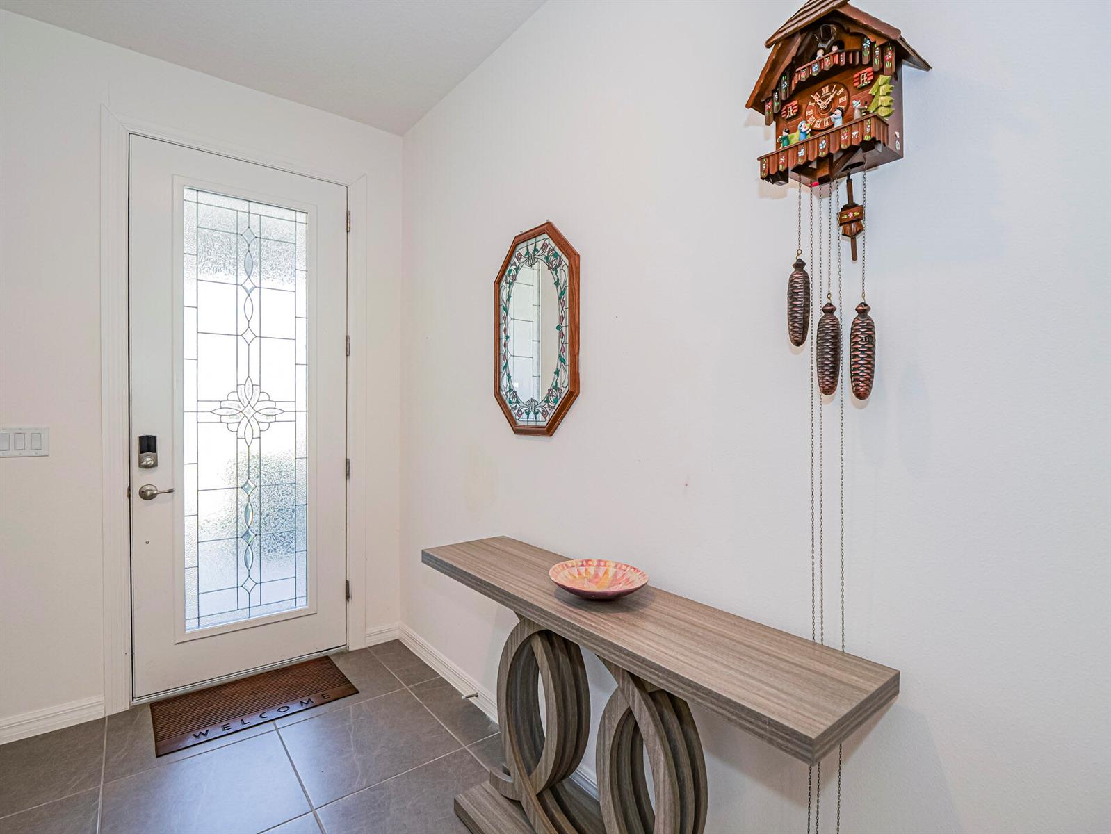 An entryway features a white door, a console table, a wall mirror, and a cuckoo clock — 1031 Topsail Lane, Sebastian FL 32958, SEBASTIAN, FL