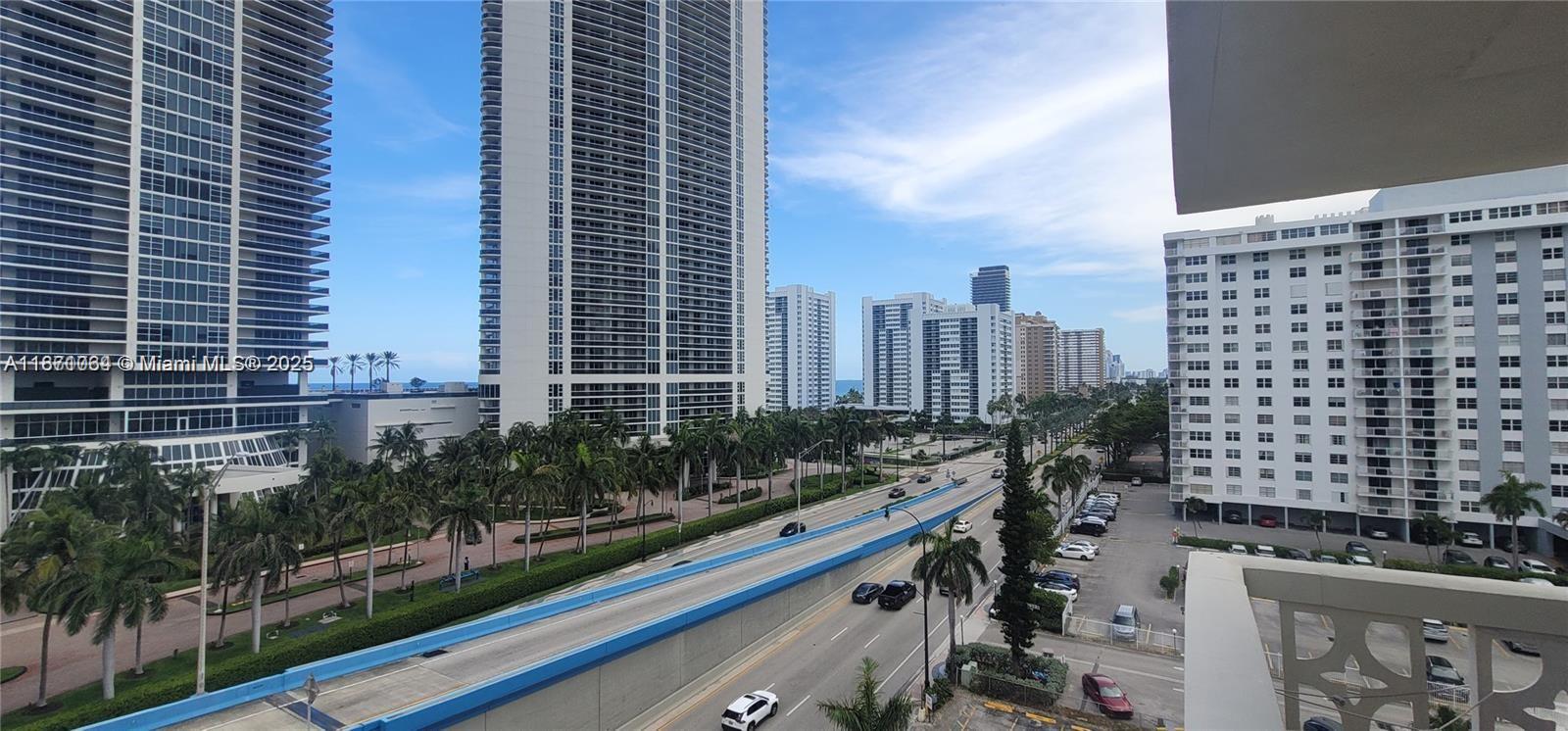 An elevated view of a multi-lane road passing between tall residential buildings and palm trees — 1825 S Ocean Dr # 814, Hallandale Beach FL 33009, HALLANDALE BEACH, FL