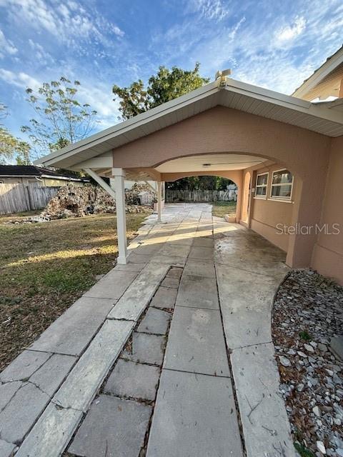 A concrete driveway leads to a covered carport attached to the side of a house — 414 AVENUE C AVENUE NE, WINTER HAVEN, FL