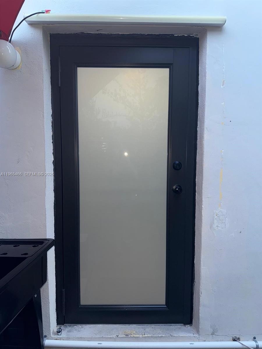 A black-framed door with a frosted glass panel is set into a white exterior wall — 13142 SW 5th St # 0, Miami FL 33184, MIAMI, FL