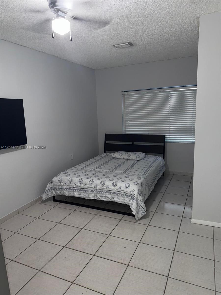 A bedroom features a bed with a dark frame, a ceiling fan, and tiled flooring — 13142 SW 5th St # 0, Miami FL 33184, MIAMI, FL