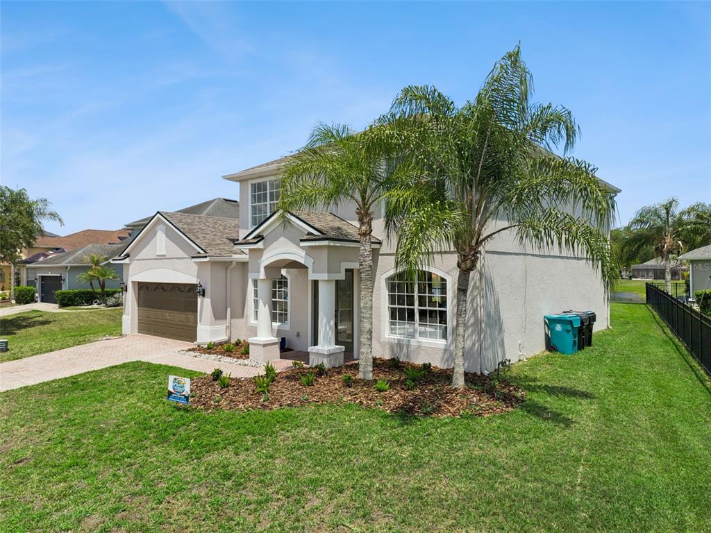 A two-story suburban house with a tan stucco exterior, a paved driveway, and palm trees — 5979 WINCHESTER ISLE RD, ORLANDO, FL