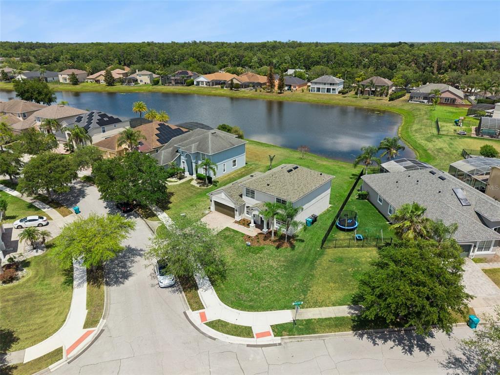 An aerial view shows suburban houses with swimming pools and lawns bordering a large lake — 5979 WINCHESTER ISLE RD, ORLANDO, FL