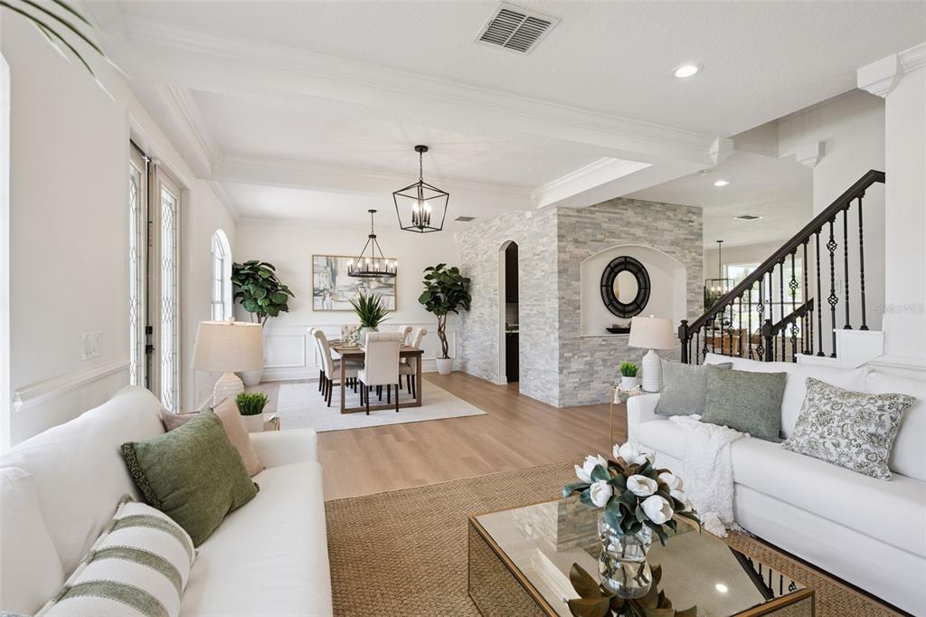 A bright open-concept living and dining area features white sofas, wood flooring, and stone accents — 5979 WINCHESTER ISLE RD, ORLANDO, FL