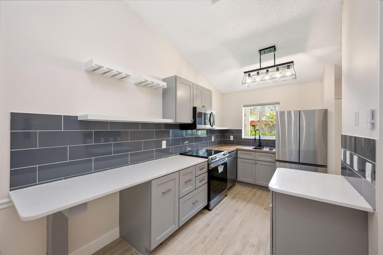 A kitchen features gray cabinets, white countertops, a gray subway tile backsplash, and stainless appliances — 5214 Stacy Street # 3, FL 33417, FL