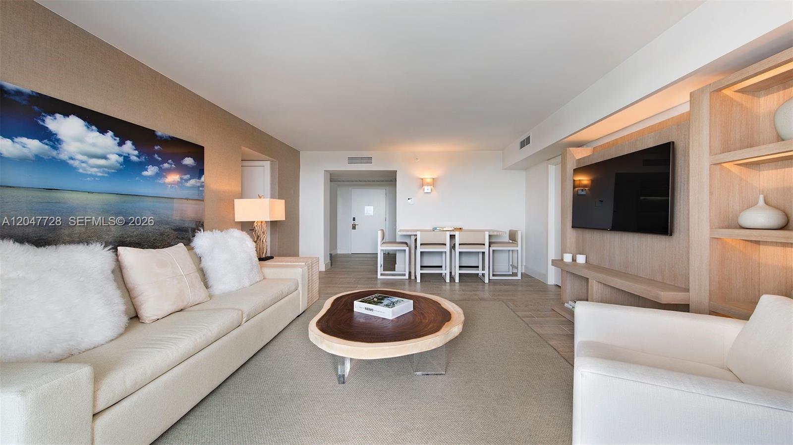 A living room features a light-colored sofa, a wood-slab coffee table, and a wall-mounted television — 102 24th St # 1245, Miami Beach FL 33139, MIAMI BEACH, FL