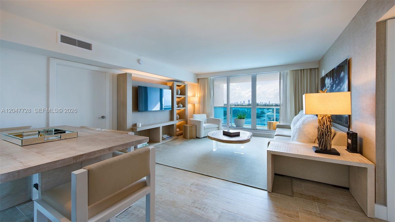 A modern living room features wood-look tile floors, a neutral color palette, and a balcony view — 102 24th St # 1245, Miami Beach FL 33139, MIAMI BEACH, FL
