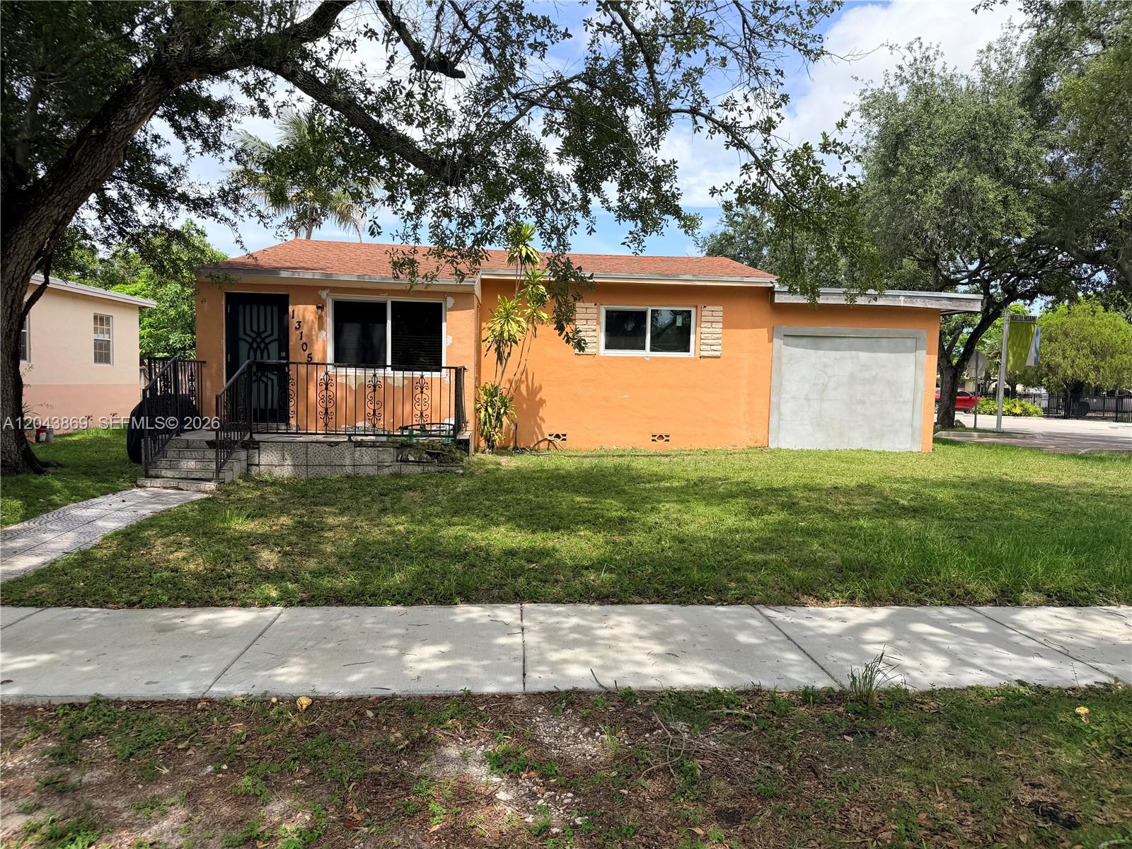 A single-story orange house with a front porch, metal railings, and a converted garage — 13105 NW 12th Ave, North Miami FL 33168, NORTH MIAMI, FL