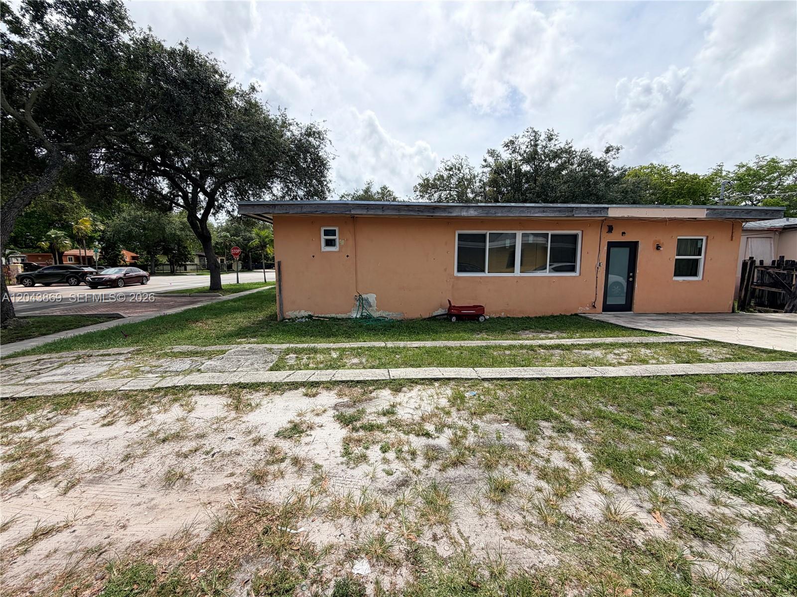 A single-story peach-colored house features a flat roof, white-framed windows, and a front entry door — 13105 NW 12th Ave, North Miami FL 33168, NORTH MIAMI, FL
