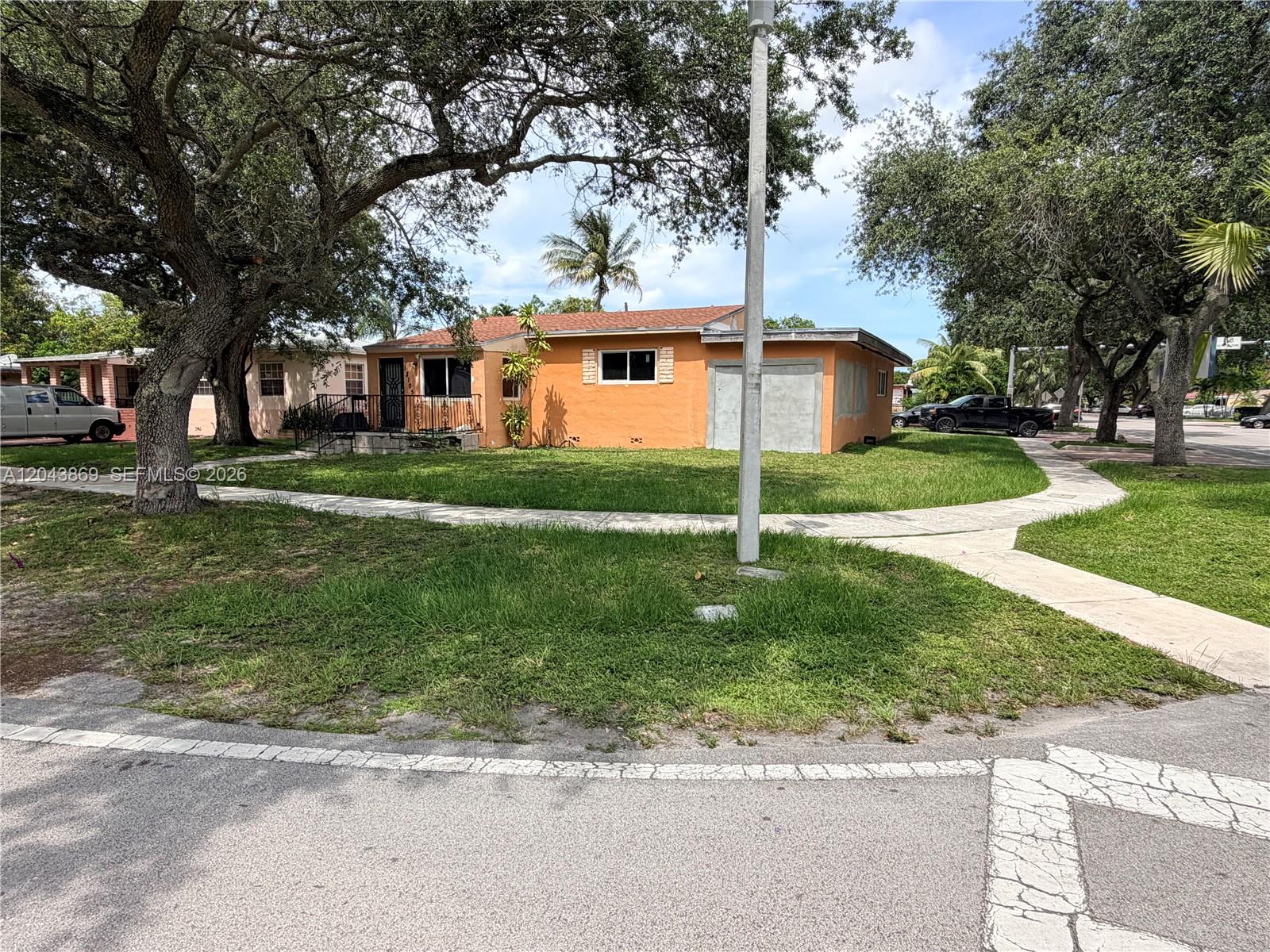 A single-story orange house with a flat roof sits on a corner lot with trees — 13105 NW 12th Ave, North Miami FL 33168, NORTH MIAMI, FL
