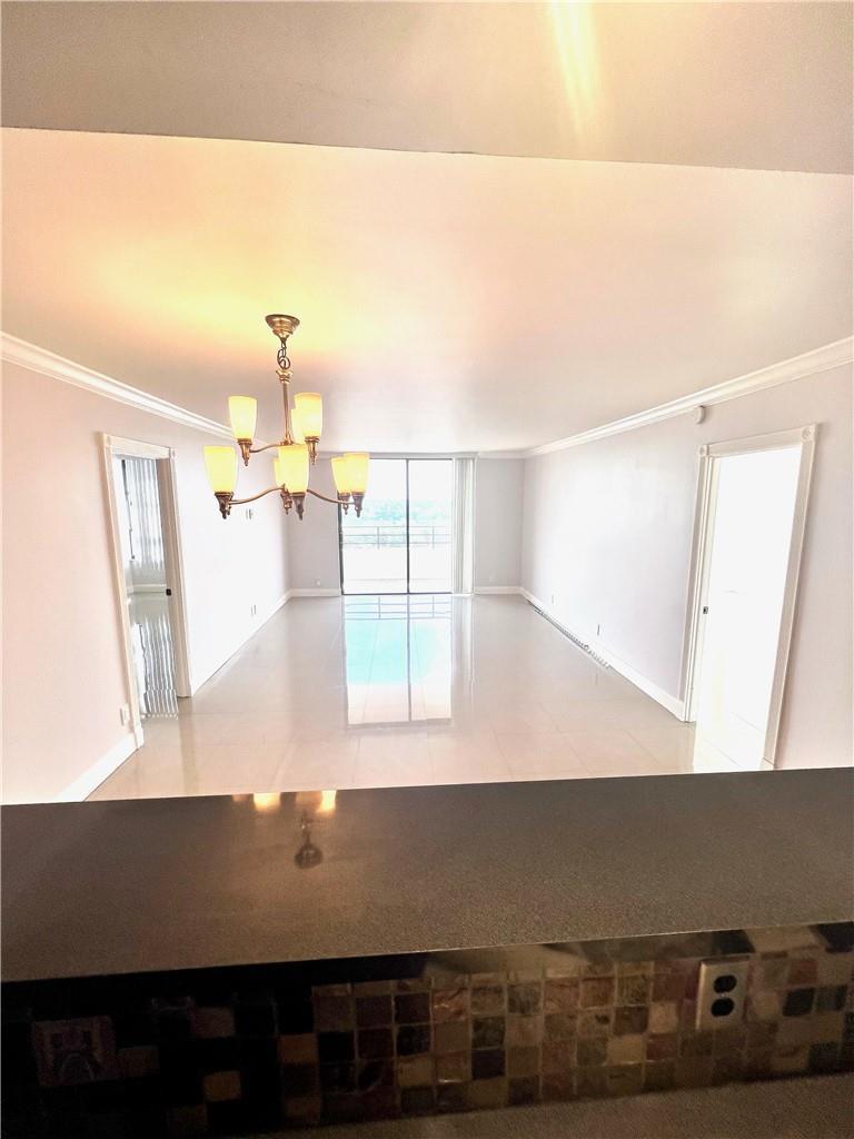 An open-concept living area features light-colored tile flooring, a chandelier, and a sliding glass door — 600 Three Islands Boulevard # 1108, Hallandale Beach FL 33009, HALLANDALE BEACH, FL