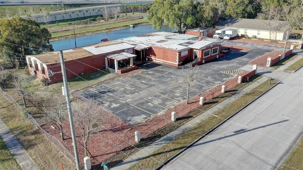 An aerial view shows a red brick commercial building with a parking lot and pond — 1416 30TH ST, ORLANDO, FL