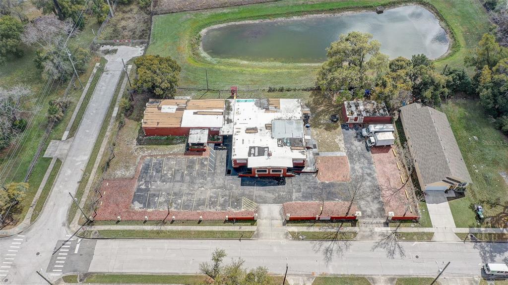 An aerial view shows a commercial building with a parking lot, adjacent house, and pond — 1416 30TH ST, ORLANDO, FL