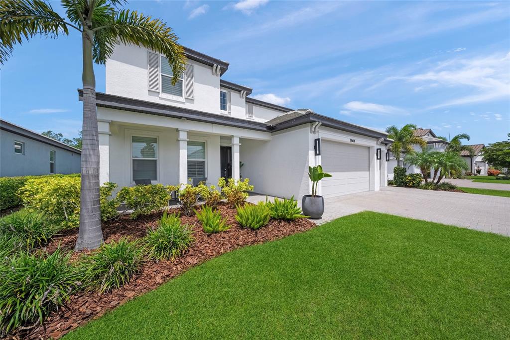 A two-story white house with a paved driveway, a front porch, and a manicured lawn — 11504 APPLE TREE CIRCLE, BRADENTON, FL